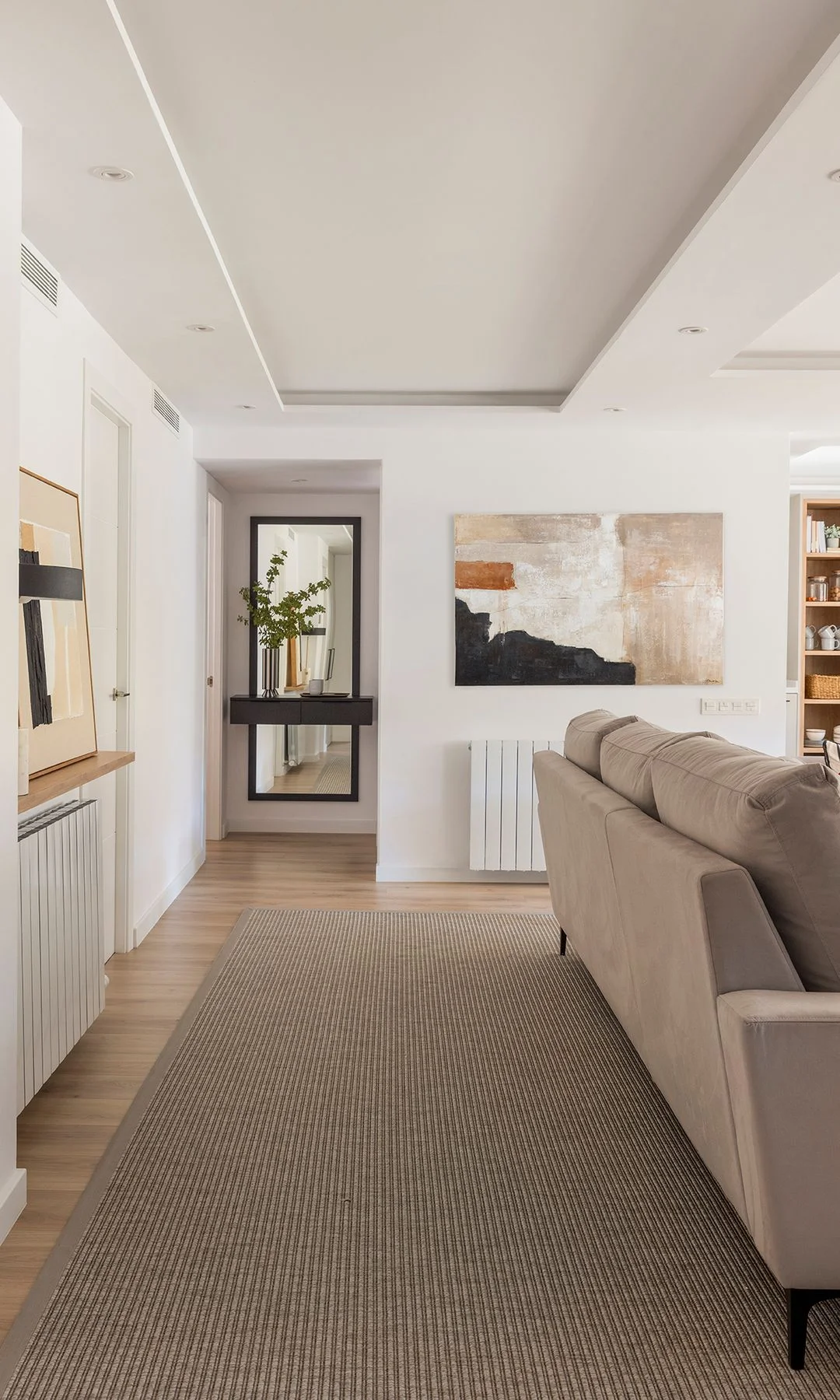 Salón luminoso de un piso moderno, con sofá, mesa de centro y salida a la terraza